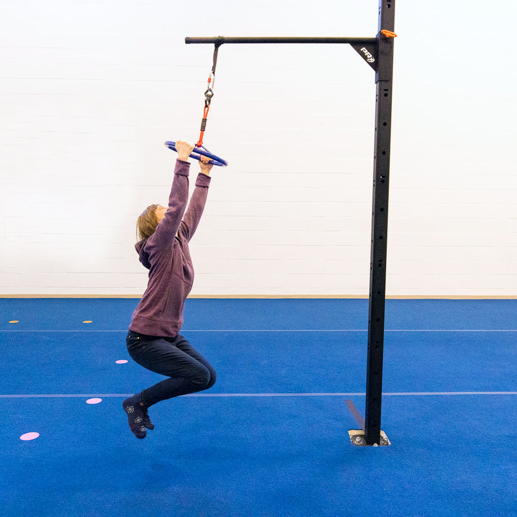 A young woman hanging on a ninja wheel