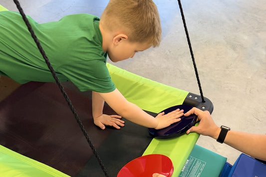 A boy doing occupational therapy on a platform swing