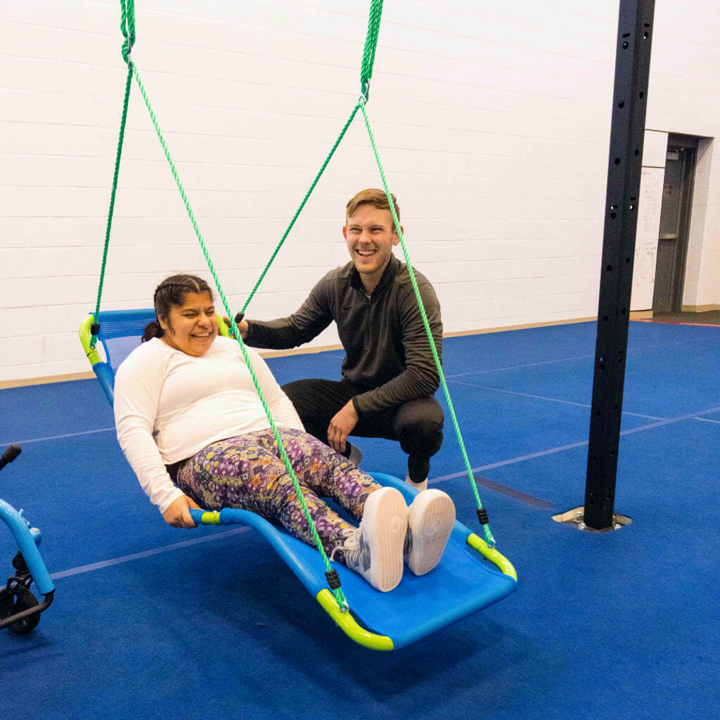 A young woman enjoying the hanging lounge swing with the help of an OT