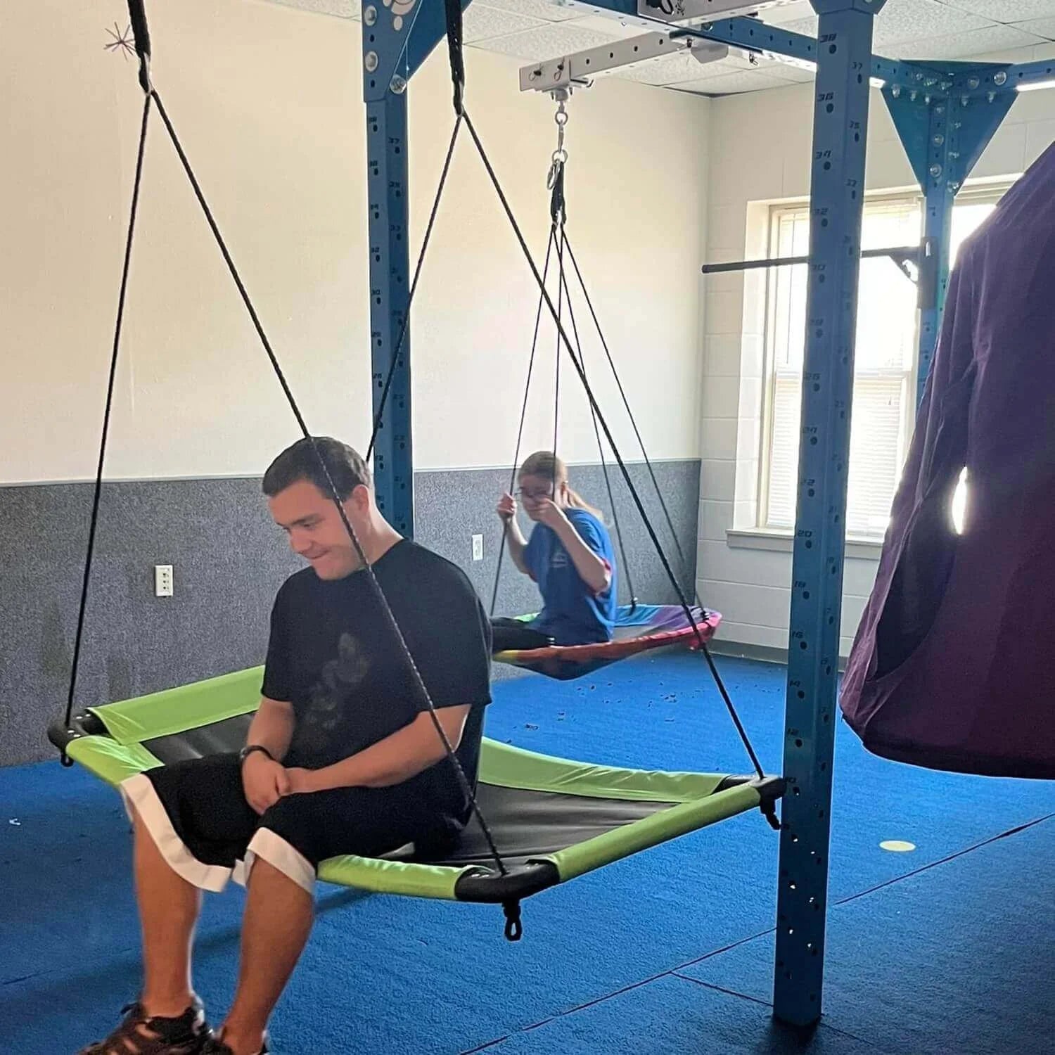 Adults with sensory needs enjoying swinging indoors
