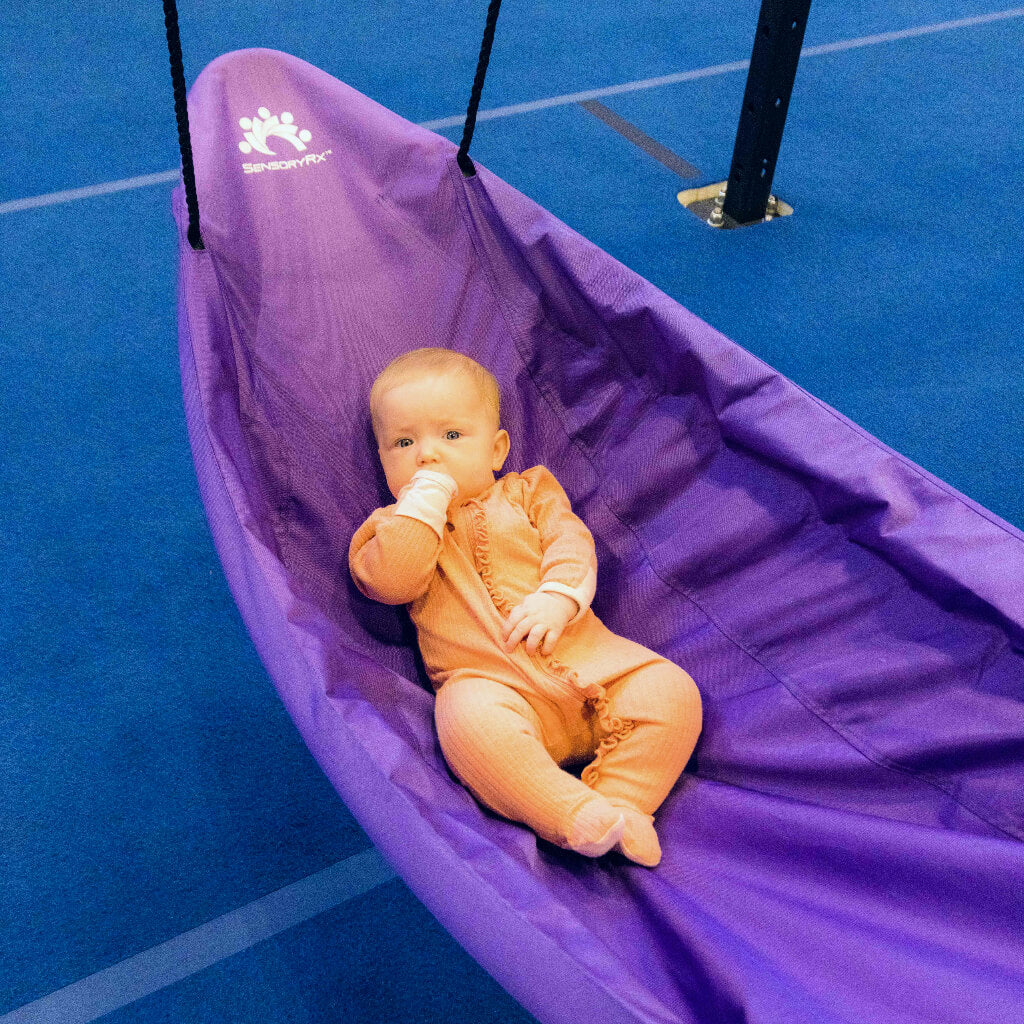 Baby girl relaxing in sensory canoe swing