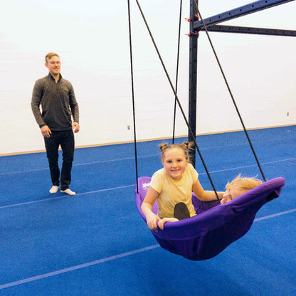 Two girls in a canoe swing being pushed by an occupational therapist