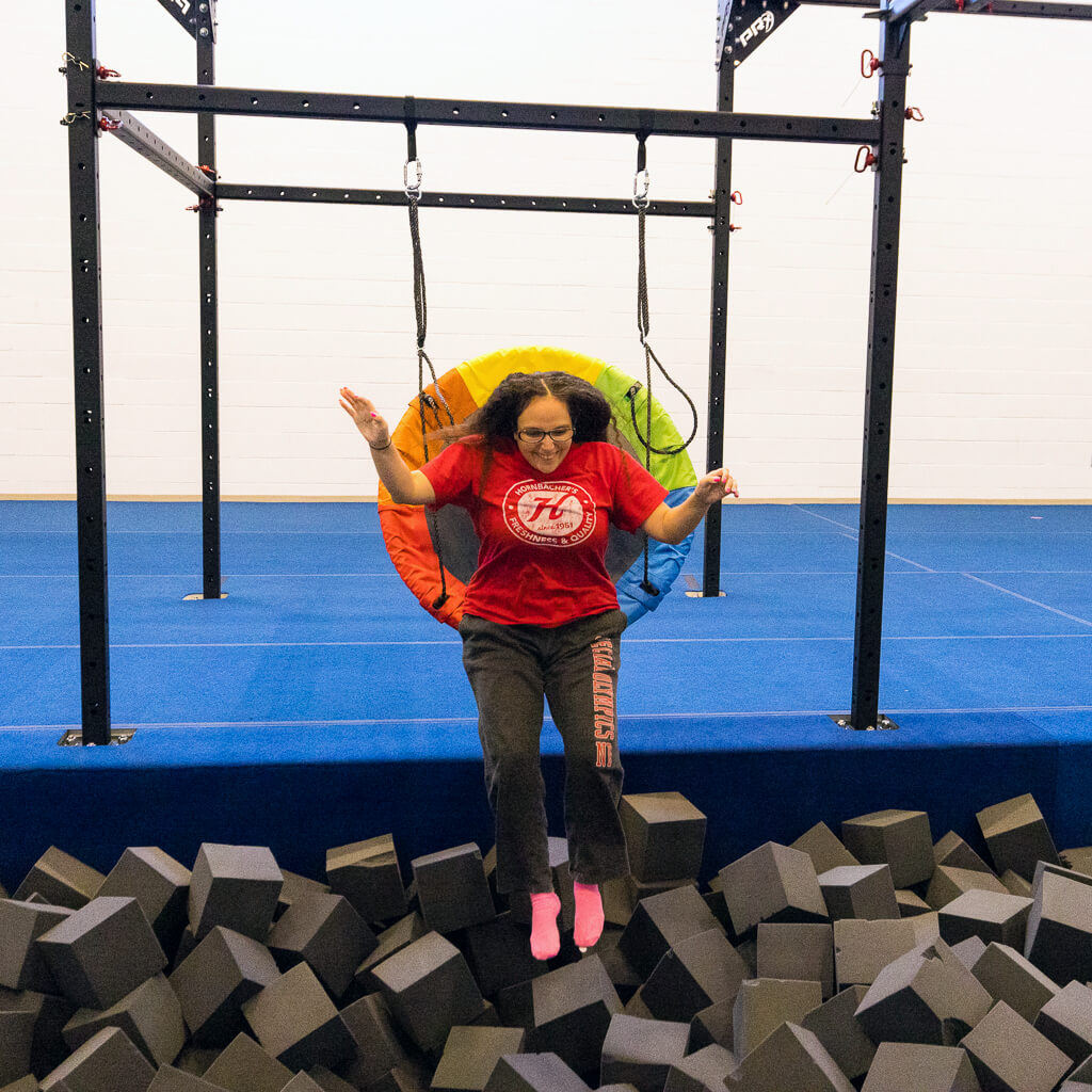 A woman jumping into a foam pit from a saucer swing