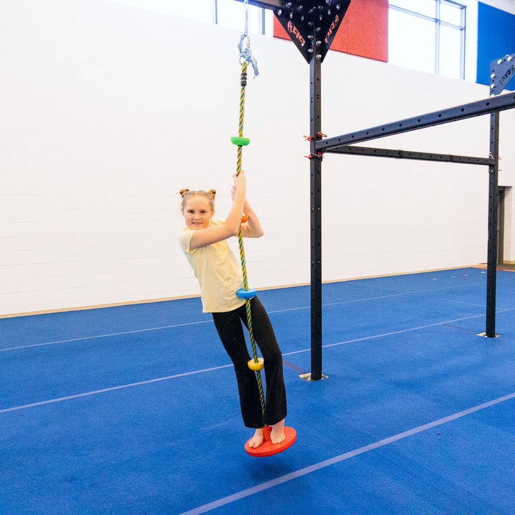 A girl hanging on a climbing rope with discs