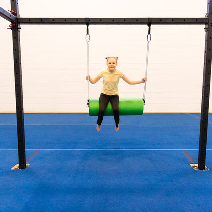 A girl swinging on a round green bolster swing