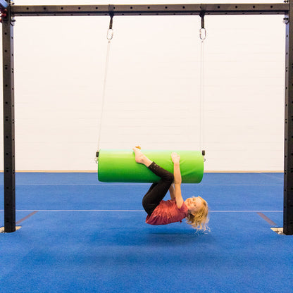 A girl hanging upside down on a round green bolster swing