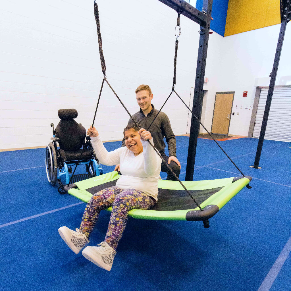 Woman with cerebral palsy enjoys swinging with an occupational therapist